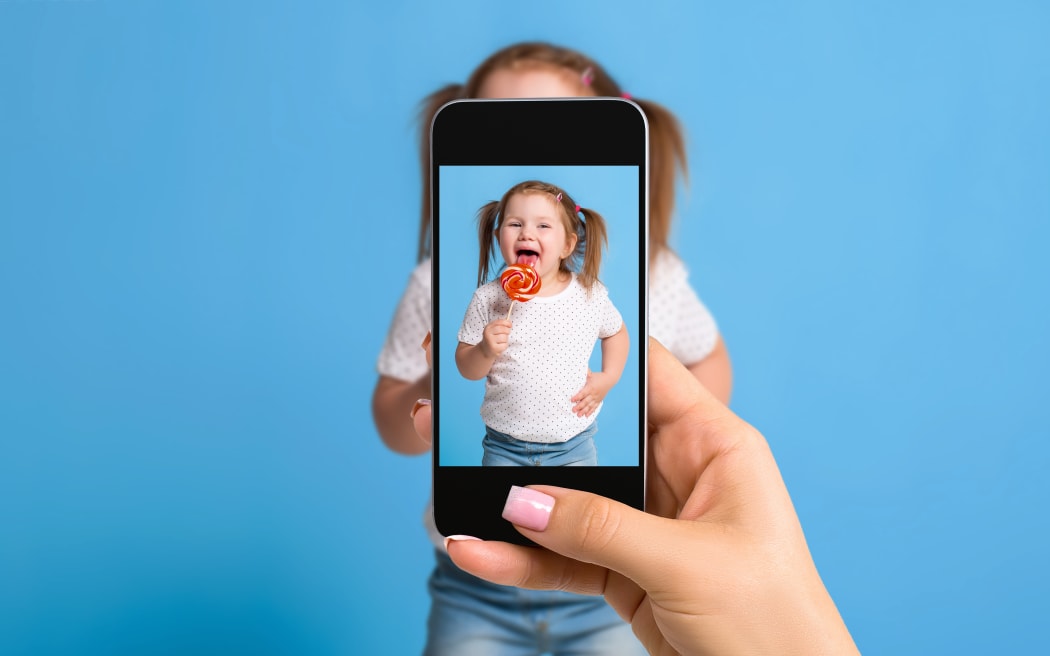 Une main de femme prenant une photo d'une petite fille avec un téléphone mobile. Focalisation sélective sur le téléphone avec le portrait d'une fille.
